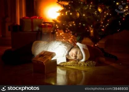 Cute girl lying under Christmas tree and looking in glowing gift box