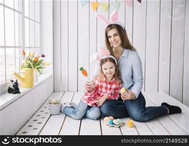 cute girl mother bunny ears sitting with easter eggs