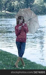 cute girl near river under her umbrella during an autumn rain