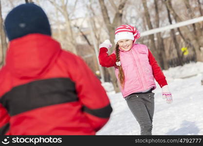 Cute girl of school age having fun in winter park. Winter activity