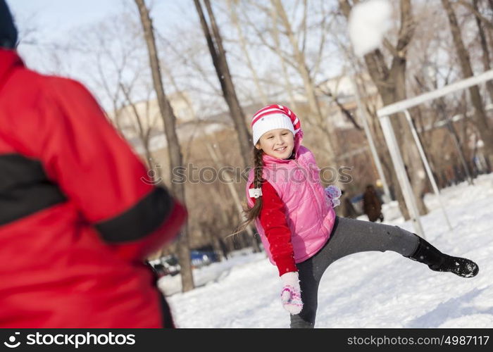 Cute girl of school age having fun in winter park. Winter activity