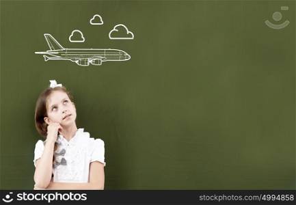 Cute girl of school age standing at blackboard. Lesson at school