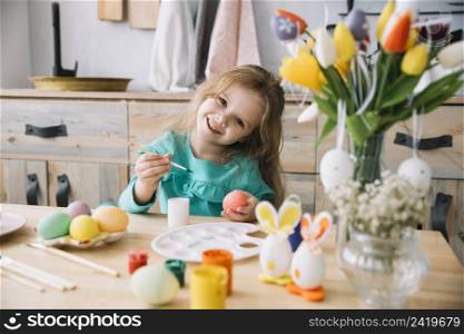cute girl painting eggs easter table