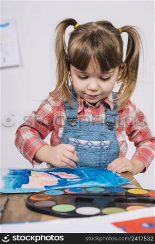 cute girl painting with blue gouache wooden table