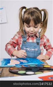 cute girl painting with blue gouache wooden table
