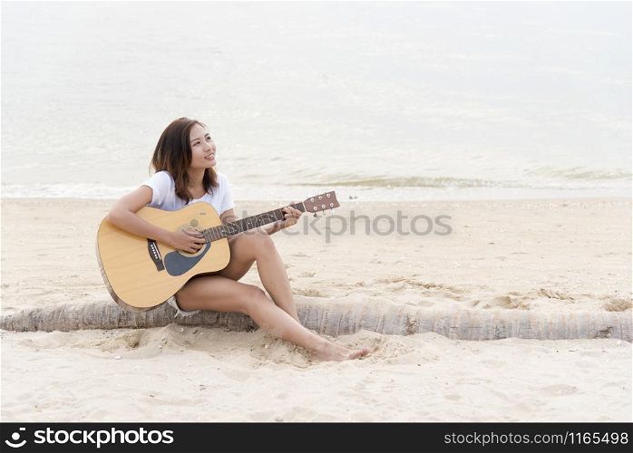 Cute girl playing guitar on the beach. Travel Concept.