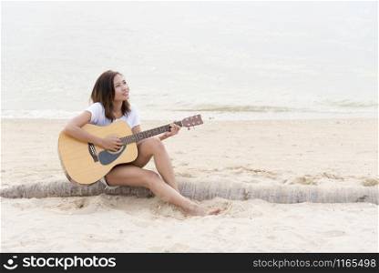 Cute girl playing guitar on the beach. Travel Concept.