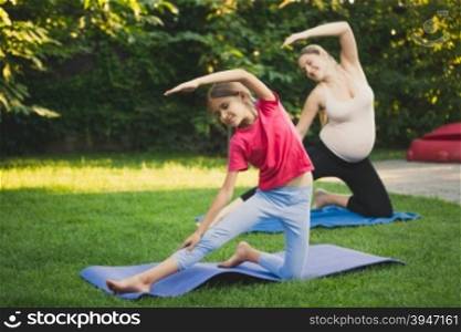 Cute girl practicing yoga with mother on grass at park