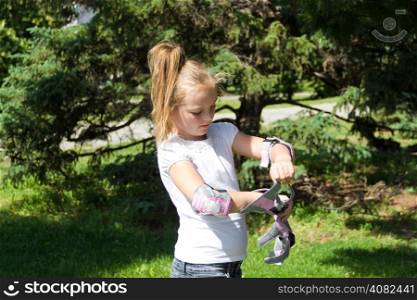 Cute girl put on roller skates in summer