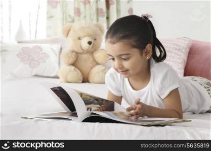 Cute girl reading book in bed