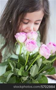 Cute girl smelling roses at home