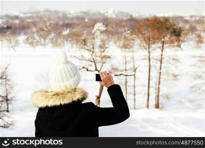 Cute Girl Taking Photos With Mobile Phone In Winter