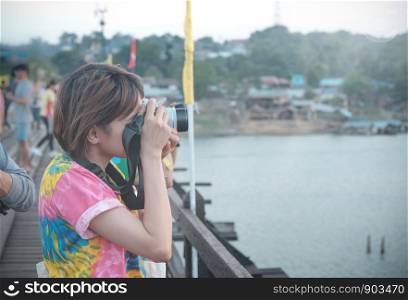 Cute girl taking pictures on a wooden bridge in the air, glowing bright sky.