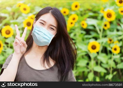 Cute girl teen happy ware face mask for protect Coronavirus Covid-19  or Air pollution or flower pollen allergy on sunflower park background