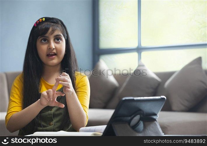 Cute girl trying to solve a math problem during her online class at home