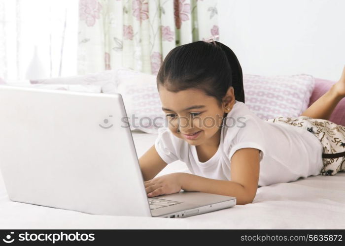 Cute girl using laptop in bed