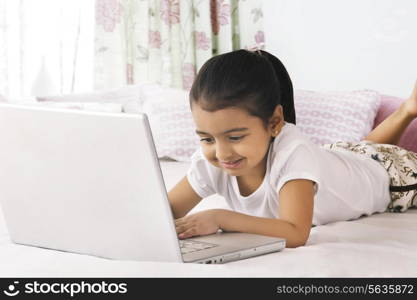 Cute girl using laptop in bed