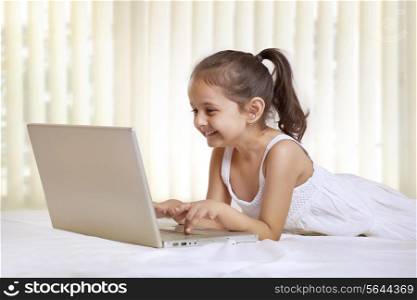 Cute girl using laptop in bedroom