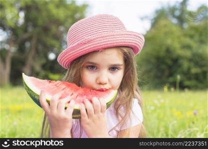 cute girl wearing pink hat eating watermelon slice park