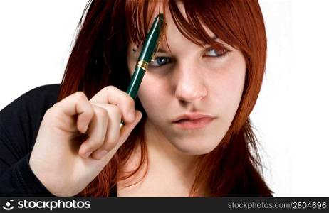 Cute girl with red hair holding a pen against her forehead and thinking. Studio shot.