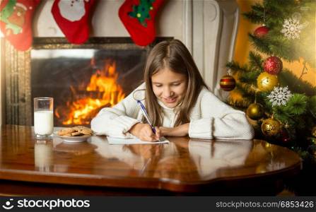 Cute girl writing letter to Santa Claus at Christmas eve