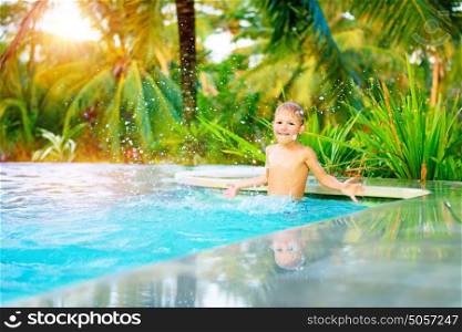 Cute happy little boy in the pool, active kid playing in the poolside, enjoying summer holidays on the exotic beach resort