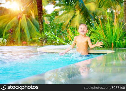 Cute happy little boy playing in the pool in nice sunny day, splashing water in the swimming pool, having fun on the beach resort, spending summer holidays with pleasure