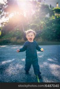 Cute happy little boy playing outdoors, sweet child standing on the street and shouting, bright children&rsquo;s emotions, enjoying life and childhood. Cute happy little boy