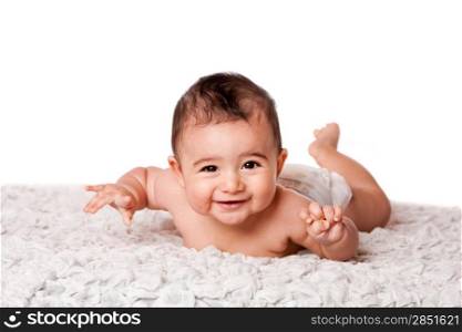 Cute happy smiling baby laying on belly on soft surface wearing diaper, looking at camera, isolated.