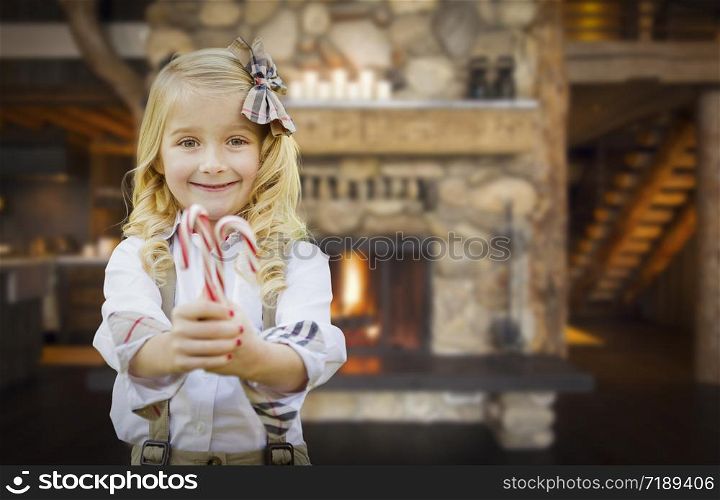 Cute Happy Young Girl Holding Candy Canes in Rustic Cabin.