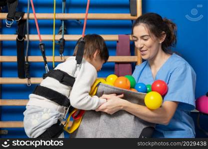 Cute kid with cerebral palsy doing musculoskeletal therapy in the hospital while laughing and having fun . High quality photo. Cute kid with cerebral palsy doing musculoskeletal therapy in the hospital while laughing and having fun .