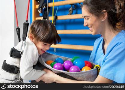 Cute kid with cerebral palsy doing musculoskeletal therapy in the hospital while laughing and having fun . High quality photo. Cute kid with cerebral palsy doing musculoskeletal therapy in the hospital while laughing and having fun .