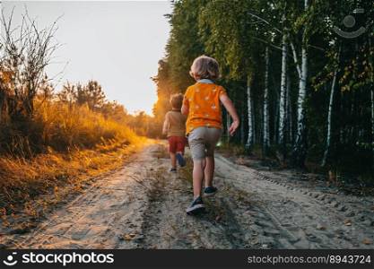Cute kids, boys runs at summer nature road. Brothers, playing outdoors. Sunset. Happy childhood. High quality photo. Cute kids, boys runs at summer nature road. Brothers, playing outdoors. Sunset.