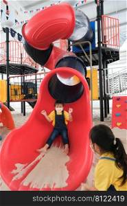 Cute kids playing on the outdoor playground. Little sisters playing slides in the park. Healthy summer activity for children.