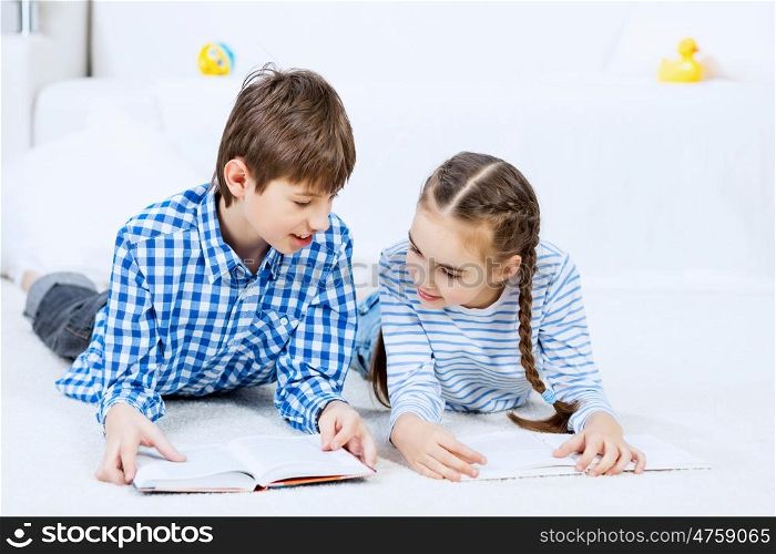 Cute kids reading books. School boy and girl laying on the floor and reading book