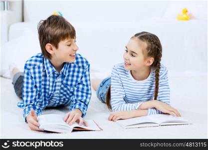 Cute kids reading books. School boy and girl laying on the floor and reading book