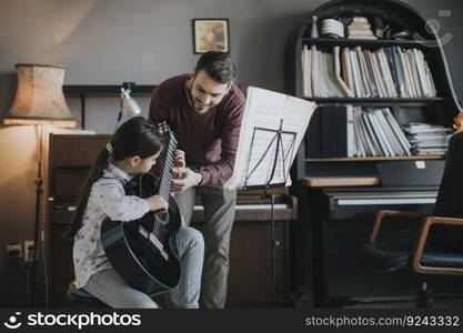 Cute litt≤girl playing guitar with herμsic teacher in the rustic apartment