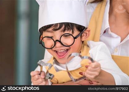 Cute little Asian happy boy interested in cooking with mother funny in home kitchen. People lifestyles and Family. Homemade food and ingredients concept. Two people baking Christmas cake and cookies