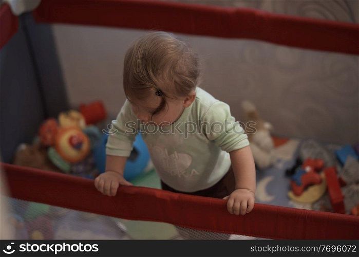 cute  little baby playing with toys in mobile bed making first steps and learnig to stand  and walk