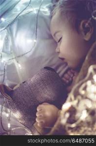 Cute little baby sleeping at home in his bed with his best friend, soft toy dog, vintage style photo with glowing lights, childhood dreams. Cute little baby sleeping