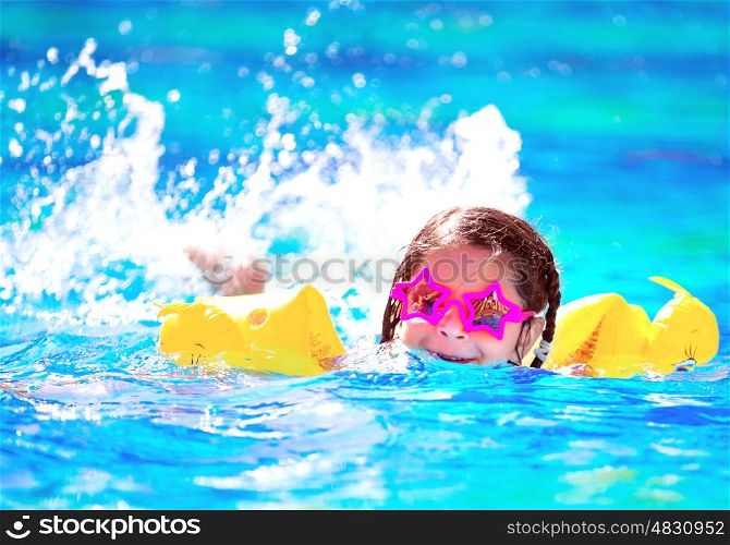 Cute little baby swiming in the pool, wearing funny sunglasses, enjoying summer weekend in aquapark, holidays and vacation concept