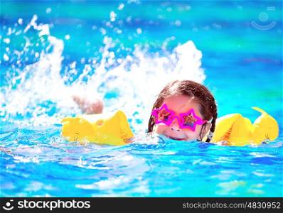 Cute little baby swiming in the pool, wearing funny sunglasses, enjoying summer weekend in aquapark, holidays and vacation concept