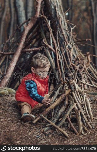 Cute little boy building a wooden hut