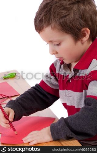 Cute little boy drawing on a red heart