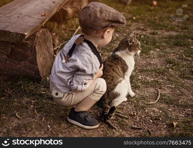 Cute, little boy enjoying an autumn warm day with a cat