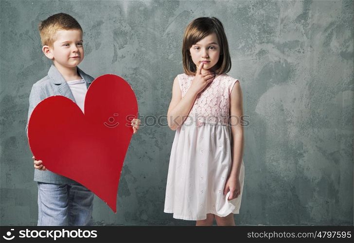 Cute little boy giving a heart to his cute sister