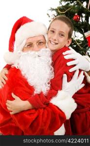 Cute little boy giving Santa Claus a big hug on Christmas morning.