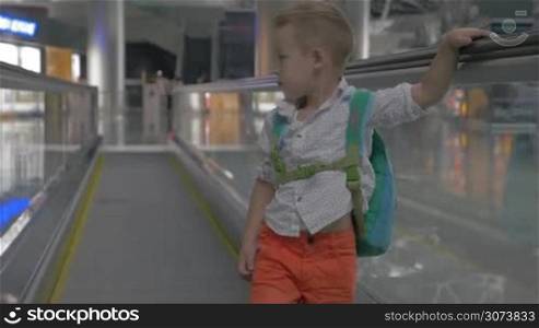 Cute little boy making faces on travelator in airport