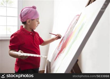 Cute little boy painting on artist&rsquo;s canvas with paintbrush