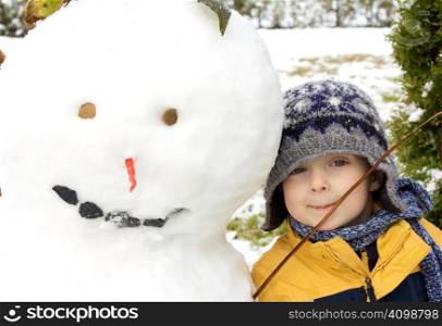 Cute little boy playing with a snowman